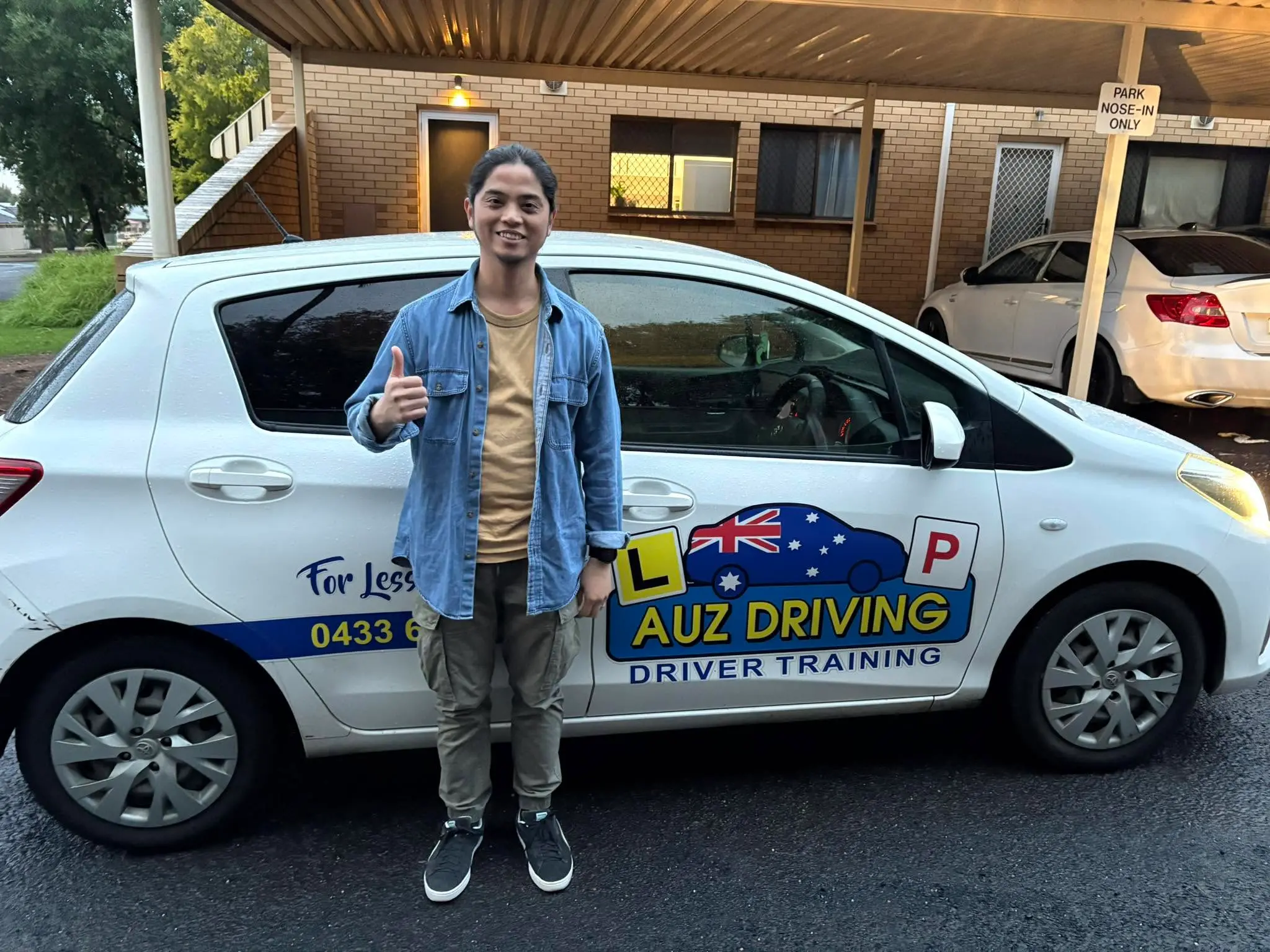 Mark has successfully passed his driving test and poses with the AUZ Driving School car