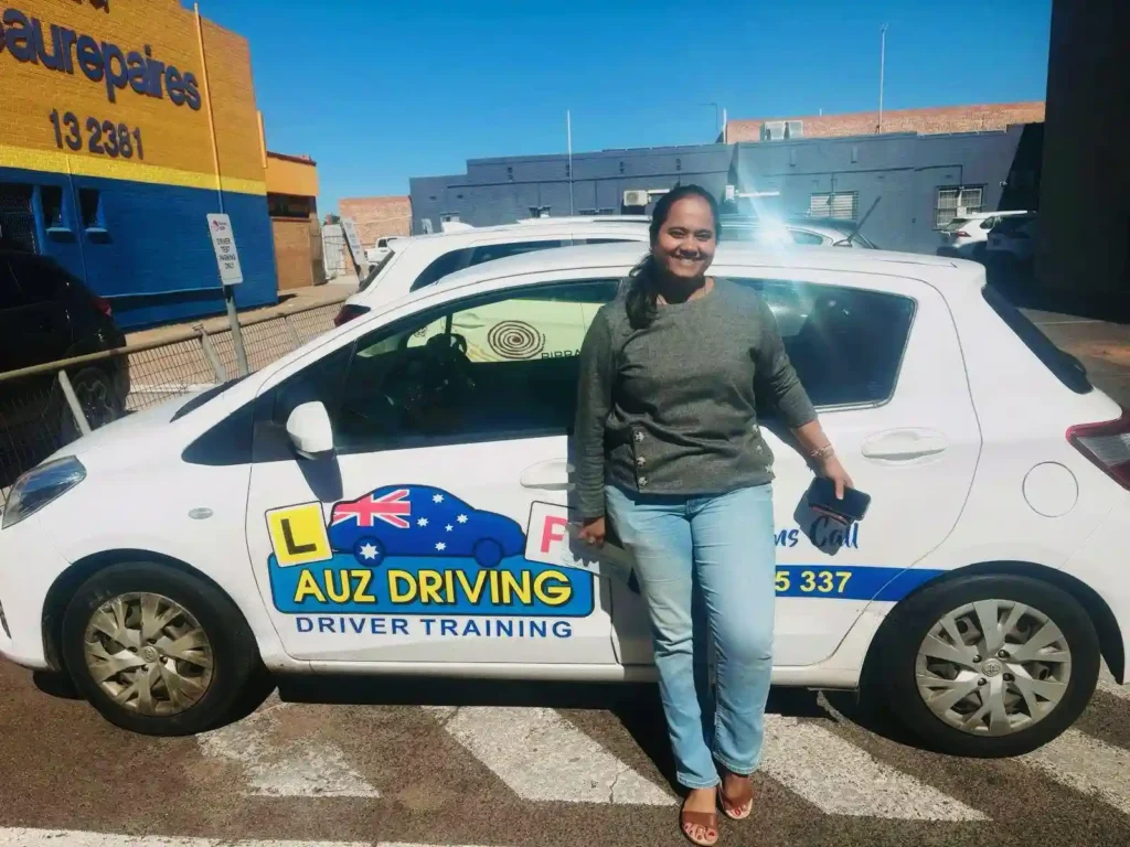 A happy female driver standing next to an AUZ Driving School dual control car after completing a refresher driving lesson in Dubbo NSW